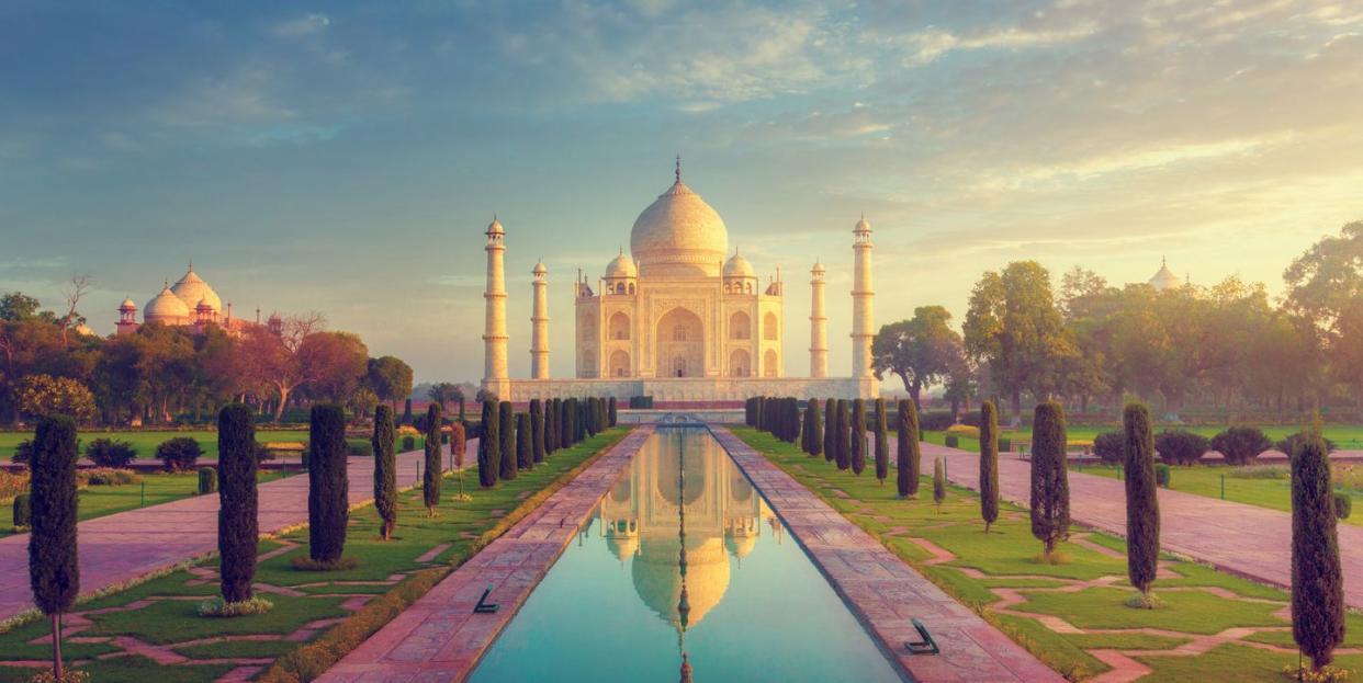 a large building with a dome and a pool of water in front with taj mahal in the background