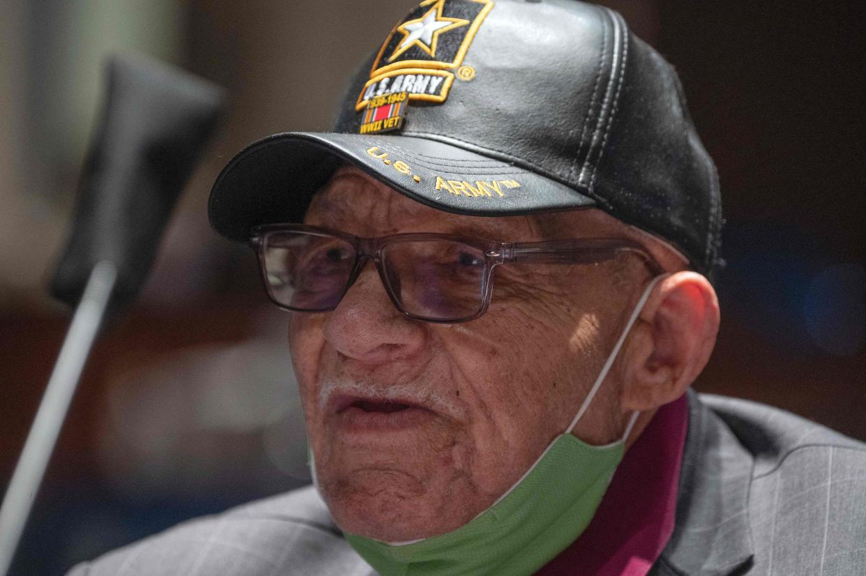 Hughes Van Ellis, wearing a U.S. Army cap and a mask below his chin, speaks with great enthusiasm.