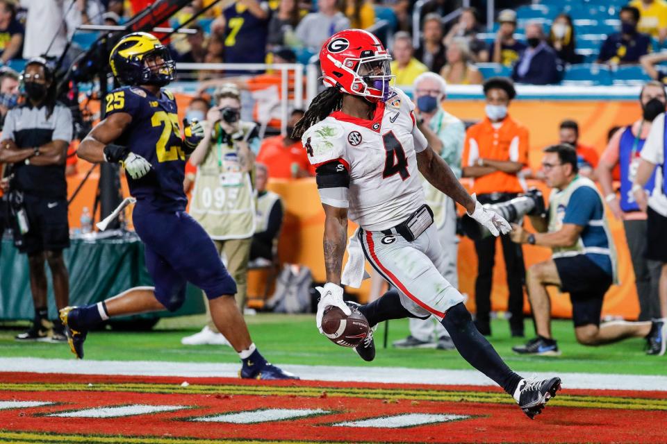 Georgia running back James Cook (4) scores a touchdown against Michigan linebacker Junior Colson (25) during the second half of the Orange Bowl at Hard Rock Stadium in Miami Gardens, Florida, on Friday, Dec. 31, 2021.