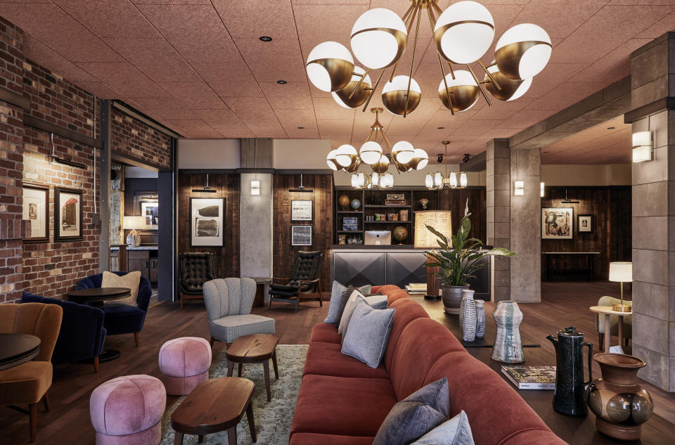 This photo shows the lobby in The Hoxton Hotel in Portland, Ore. London/L.A.-based Fettle designed Portland's Hoxton. Alongside newly-built rooms, public areas were situated in an old converted movie theater. Tailored but comfy mohair and leather seating and warm wood side tables blend with distressed rugs and displays of ceramics, plants and books. Refurbished timber and concrete beams frame the spaces. And there's a great story about the reception area's wood paneling. "We used a lot of local suppliers and material for this project," Parker says. "The area around Portland is a big producer of Maraschino cherries; the visible face of the wall is made from the outside of reclaimed cherry vats. If you look closely you can even see the imprints where the metal belts that hold the huge vats together were pressed against the wood." (Ennismore/The Hoxton via AP)