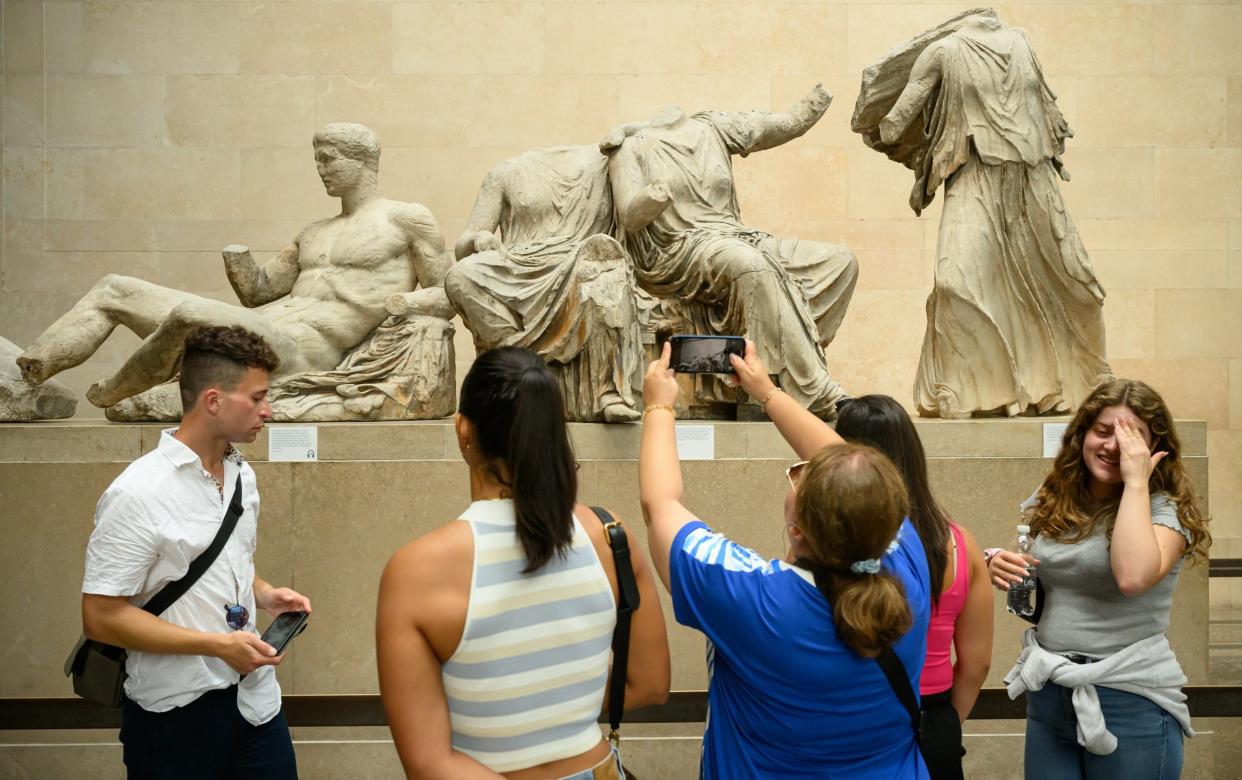 The broken statuary with tourists in front of it