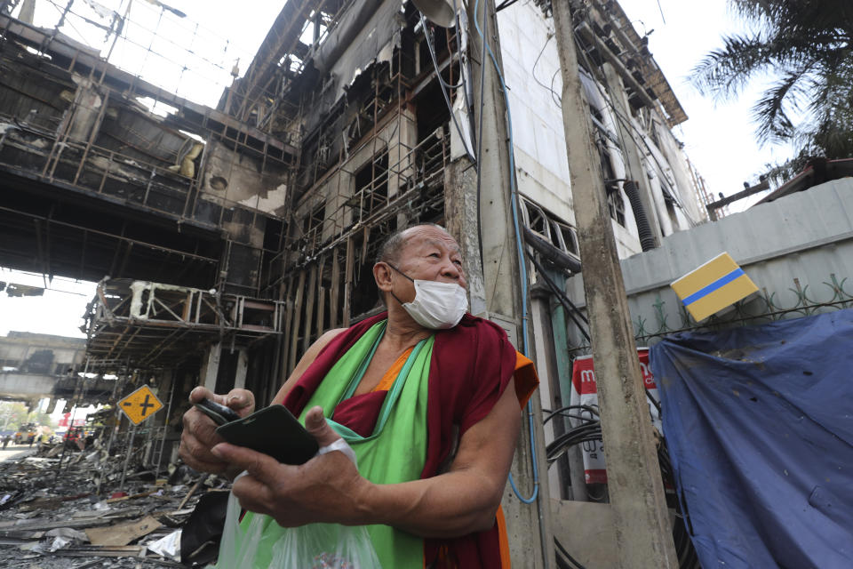 A Thai Buddhist monk visits a ruined building at the scene of a massive fire at a Cambodian hotel casino in Poipet, west of Phnom Penh, Cambodia, Friday, Dec. 30, 2022. The fire at the Grand Diamond City casino and hotel Thursday injured over 60 people and killed more than a dozen, a number that officials warned would rise after the search for bodies resumes Friday. (AP Photo/Heng Sinith)