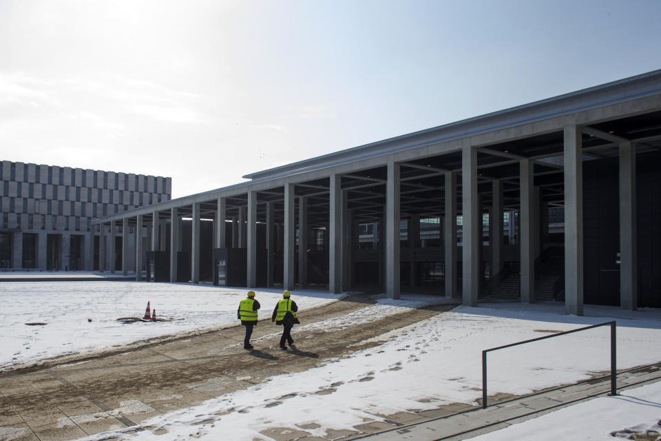 In this March 14, 2013 photo, two men walk to the main terminal of the new Berlin Brandenburg International Airport (BER) named Willy-Brandt-Flughafen in Schoenefeld near Berlin. Willy Brandt International Airport, named for Germany's famed Cold War leader, was supposed to have been up and running in late 2011, a sign of Berlin's transformation from Cold War confrontation line to world class capital of Europe's economic powerhouse. Instead it has become a symbol of how, even for this technological titan, things can go horribly wrong. After four publicly announced delays, officials acknowledged the airport won't be ready by the latest target: October 2013. To spare themselves further embarrassment, officials have refused to set a new opening date. (AP Photo/Markus Schreiber)