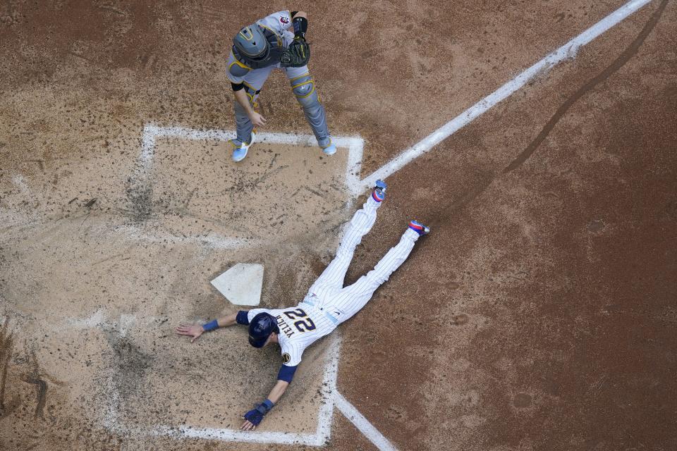 Milwaukee Brewers' Christian Yelich slides safely past Pittsburgh Pirates catcher Jason Delay during the fifth inning of a baseball game Sunday, June 18, 2023, in Milwaukee. Yelich scored from second on a hit by Jesse Winkler. (AP Photo/Morry Gash)