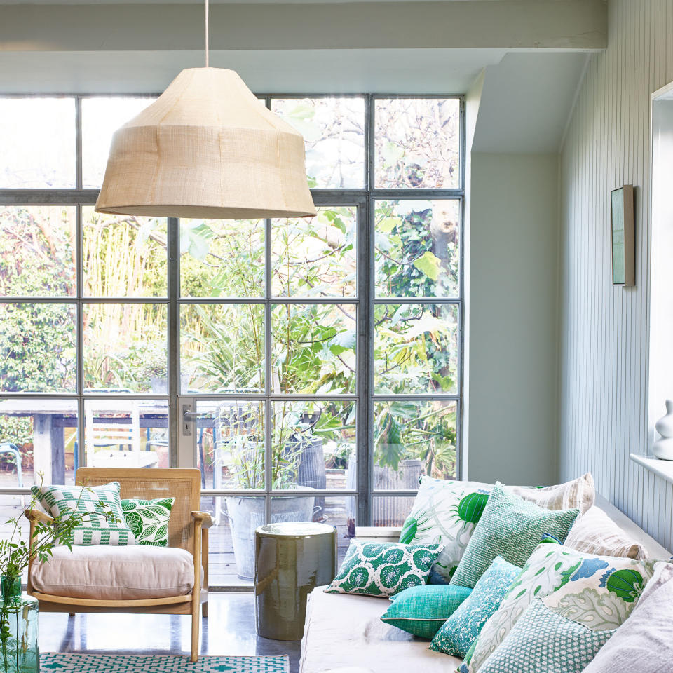 Living room with floor to ceiling windows, sofa, armchair and oversized pendant