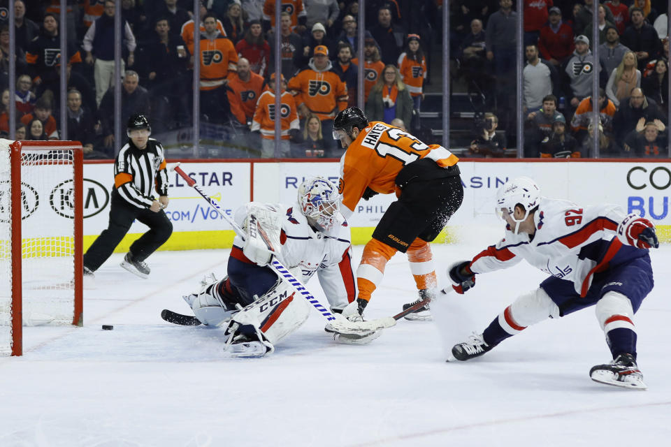 Philadelphia Flyers' Kevin Hayes, center, scores a goal from between Washington Capitals' Braden Holtby, left, and Evgeny Kuznetsov during the second period of an NHL hockey game Wednesday, Jan. 8, 2020, in Philadelphia. (AP Photo/Matt Slocum)