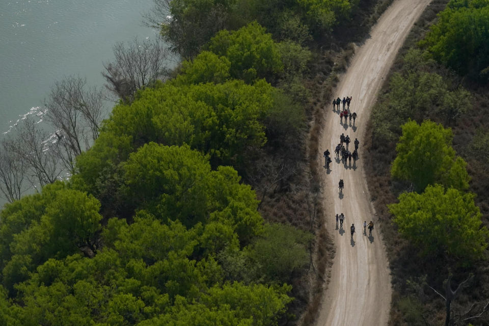 FILE - Migrants walk on a dirt road along the Rio Grande in Mission, Texas, on March 23, 2021, after crossing the U.S.-Mexico border. Within his first month in office, President Joe Biden signed a slew of executive actions to undo Trump-era policies and backed legislation to provide a path to citizenship for millions in the country illegally. He stacked his administration with immigrant advocates eager to push back against what they saw were anti-immigrant policies by Trump. (AP Photo/Julio Cortez, File)