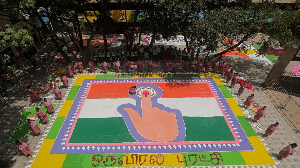 A teacher at a school in Chennai, India, puts the finishing touches on a Rangoli, a traditional work of art made of colored powder, depicting an Indian flag and a woman's finger marked with indelible ink to raise awareness and encourage people to vote in the next general elections.  - R. Parthibhan/AP