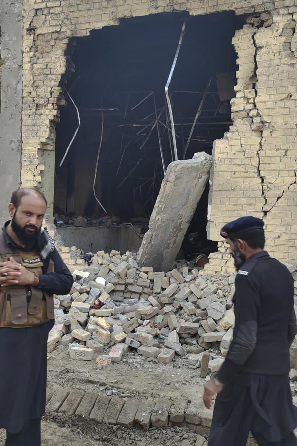 Police officers examine damages on the site of a bombing at a police station on the outskirts of Dera Ismail Khan, Pakistan, Tuesday, Dec. 12, 2023. A suicide bomber detonated his explosive-laden vehicle at a police station's main gate in northwest Pakistan on Tuesday, killing several policemen and wounding more than dozen others, officials said. Some militants also opened fire and a shootout between them and security forces was still ongoing, police officer Kamal Khan said. (AP Photo)