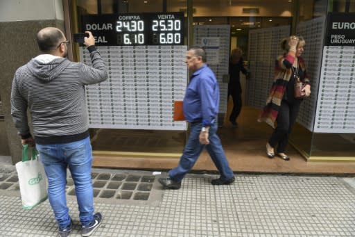 Currency exchange values are displayed on the buy-sell board of an exchange business in Argentina, where the peso has plummeted to a new low