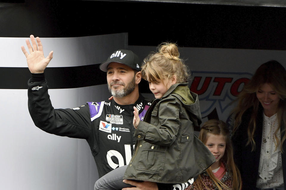 FILE - In this March 1, 2020, file photo, Jimmie Johnson is introduced to the crowd during activities as he carries his youngest daughter Lydia as his oldest daughter Genevieve and wife Chandra follow prior to a NASCAR Cup Series auto race in Fontana, Calif. Jimmie Johnson wanted to retire from full-time racing to step away from NASCAR's 11-month grind. The coronavirus pandemic has brought his final season to an unexpected pause, and now the seven-time champion isn't sure what his future holds. (AP Photo/Will Lester, File)