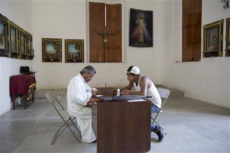 Atilio Gonzalez (L), a priest of the Southern Cemetery for the last 24 years, talks with the relative of a crime victim before the victim's burial at the Southern Cementery in Caracas January 28, 2014. REUTERS/Carlos Garcia Rawlins