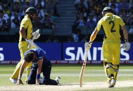 England's Steven Finn (C) reacts after failing to stop a shot from Australia's Aaron Finch (L), as Australia's captain George Bailey (R) looks on, during their Cricket World Cup match at the Melbourne Cricket Ground (MCG) February 14, 2015. REUTERS/Brandon Malone