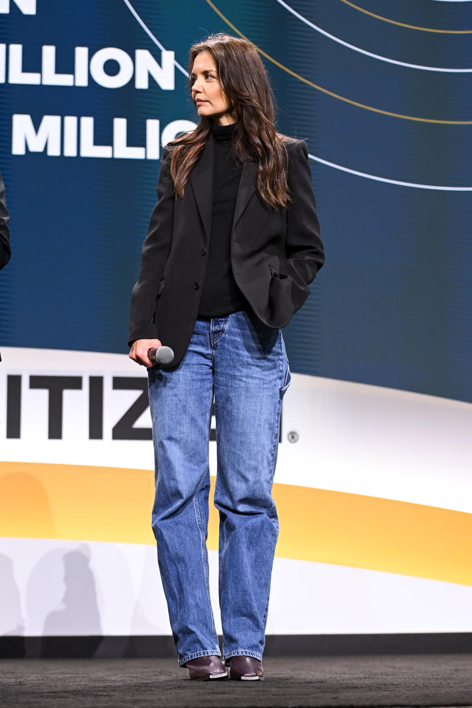 Katie Holmes wears a black turtleneck with a matching blazer on top, boyfriend jeans and dark purple leather boots. - Credit: Getty