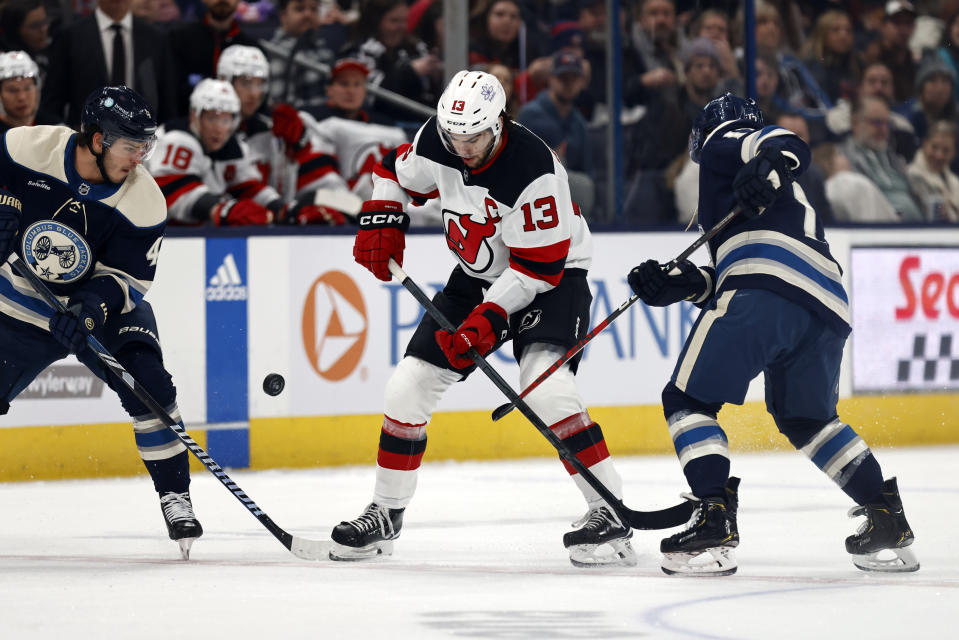 New Jersey Devils forward Nico Hischier, center, works for the puck between Columbus Blue Jackets forwards Cole Sillinger, left, and Justin Danforth, right, during the second period an NHL hockey game in Columbus, Ohio, Saturday, Dec. 16, 2023. (AP Photo/Paul Vernon)