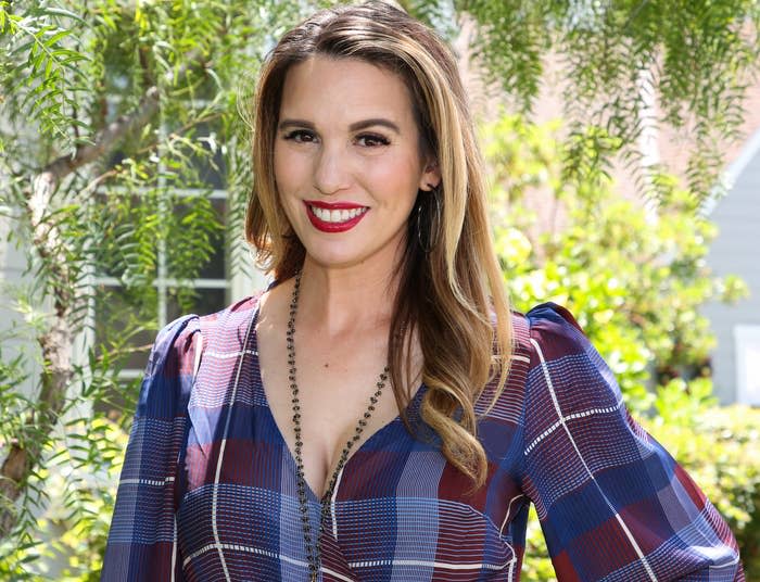 Christy smiles while wearing a blue and red plaid wrap dress