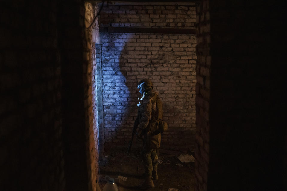 A Ukrainian serviceman walks in a basement used as a bomb shelter during Russian attacks in a village recently retaken by Ukrainian forces near Kharkiv, Ukraine, Saturday, April 30, 2022. (AP Photo/Felipe Dana)