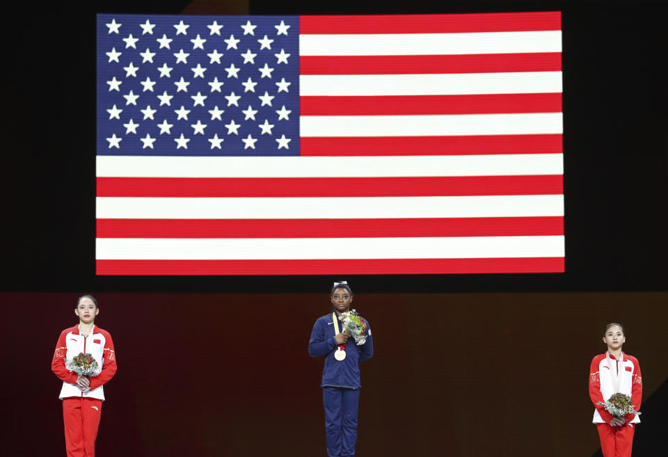 Simone Biles of the United States, center and gold medal, Liu Tingting of China, left and silver medal, and Li Shijia of China, right and bronze medaL, listen to the national anthem during the award ceremony for the balance beam in the women's apparatus finals at the Gymnastics World Championships in Stuttgart, Germany, Sunday, Oct. 13, 2019. (AP Photo/Matthias Schrader)