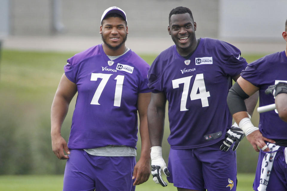 Minnesota Vikings linemen Christian Darrisaw (71) and Oli Udoh (74) smile as they watch drills during NFL football training camp Wednesday, July 28, 2021, in Eagan, Minn. (AP Photo/Bruce Kluckhohn)