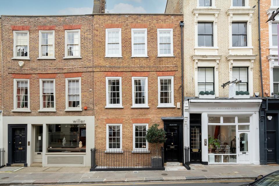 The handsome brick home rests sandwiched between shops on a quiet street, and is sited just a short walk from Kensington Palace and Holland Park.