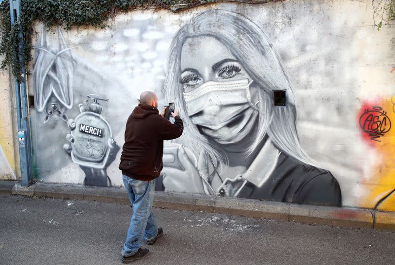 Artist Perez takes a picture of his graffiti of a cashier to pay tribute to essential workers in Gland