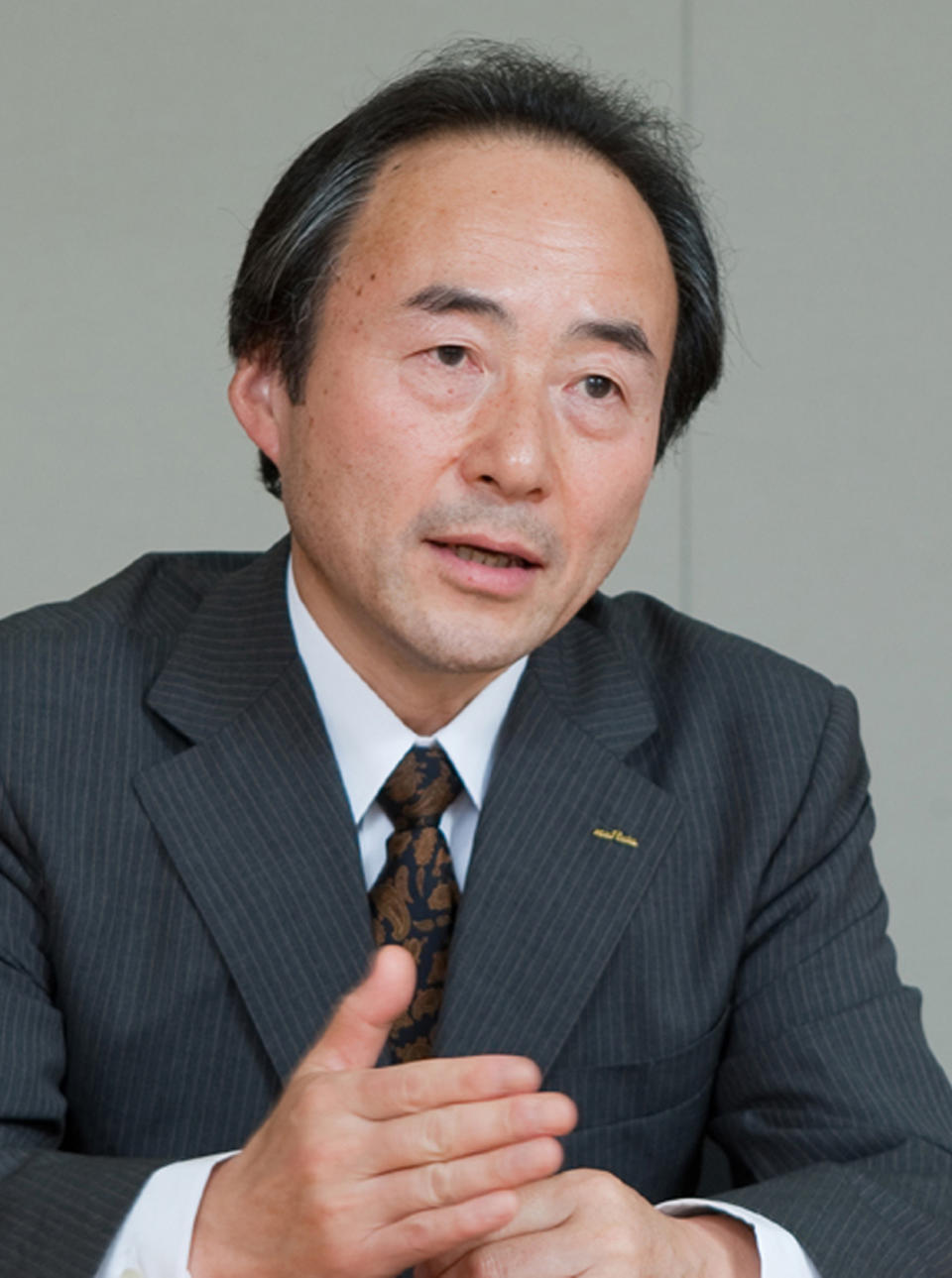 In this undated photo released by Murata Manufacturing Co., Murata Executive Vice President Yukio Hamaji, who heads the component business, speaks about development of its latest capacitor, measuring just 0.25 millimeter by 0.125 millimeter at the Murata headquarters in Nagaokakyo, Kyoto Prefecture, central Japan. Hamaji said that building something that small, each composed of even tinier layers of material to store electricity, is a challenge, requiring precision in preparing raw materials and baking the ceramic. “This is so small you can barely see it, especially if you need bifocals,” he told The Associated Press. (AP Photo/Murata Manufacturing Co.) NO SALES