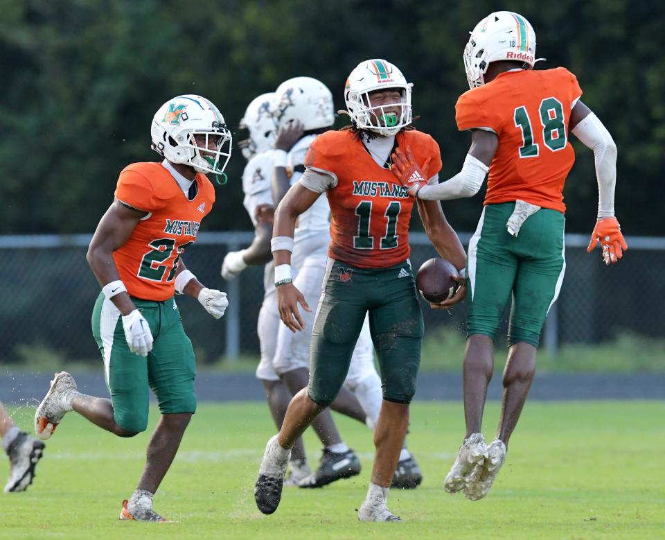 Mandarin's Drake Stubbs (11) celebrates his first quarter interception with teammates Tyler Jackson (22) and Joshua Burton (18) with just under 6 minutes to play in the first quarter. The Atlantic Coast Stingrays traveled to Mandarin to play the Mustangs in High School football Friday, September 15, 2023.