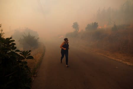 A villager runs next to a fire at the small village of Colos