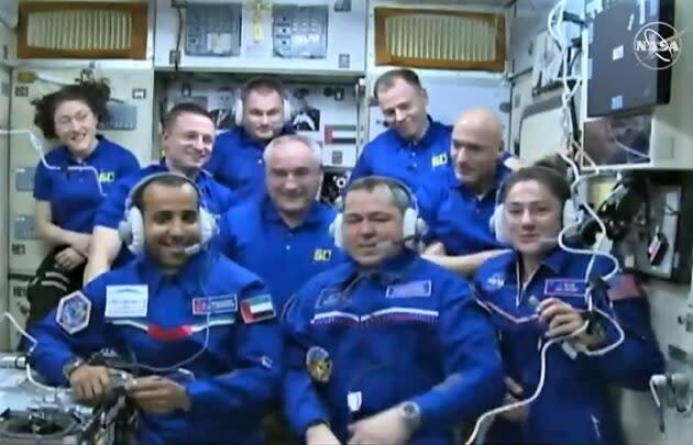 Nine crew members face the camera on the space station during a video conference. (NASA via YouTube)