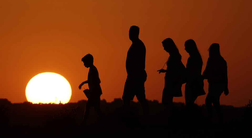 FILE - In this July 21, 2016, file photo, the sun sets beyond visitors to Liberty Memorial on Thursday, July 21, 2016, as the temperature hovers around 100 degrees in Kansas City, Mo. For the third straight year, Earth set a record for the hottest year, NOAA and NASA announced. NASA says 2016 was warmer than 2015 - by a lot. It's mostly global warming with a little assist from the now-gone El Nino. (AP Photo/Charlie Riedel, File)