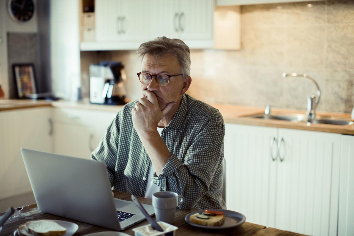 Man sitting in kitchen while on computer.