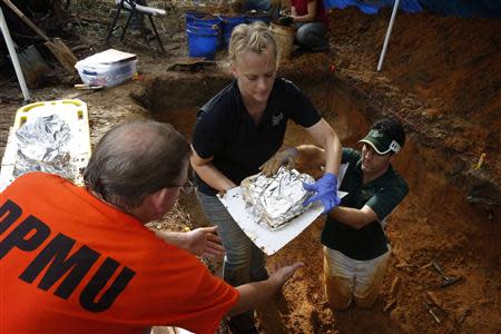 Jason Byrd (L) helps University of South Florida assistant professor Erin Kimmerle (C) and assistant professor Christian Wells remove remains from the cemetery at the now closed Arthur G. Dozier School for Boys in Marianna, Florida, September 2, 2013. REUTERS/Edmund D. Fountain/Pool