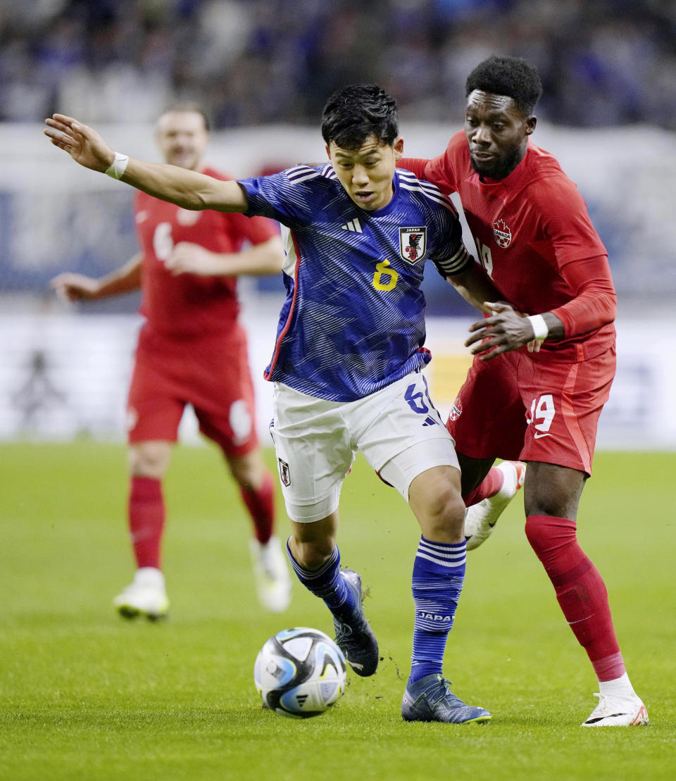 Wataru Endo, left, of Japan, and Alphonso Davies of Canada vie for the ball during a friendly soccer match in Niigata, northern Japan, Friday, Oct. 13, 2023. (Kyodo News via AP)