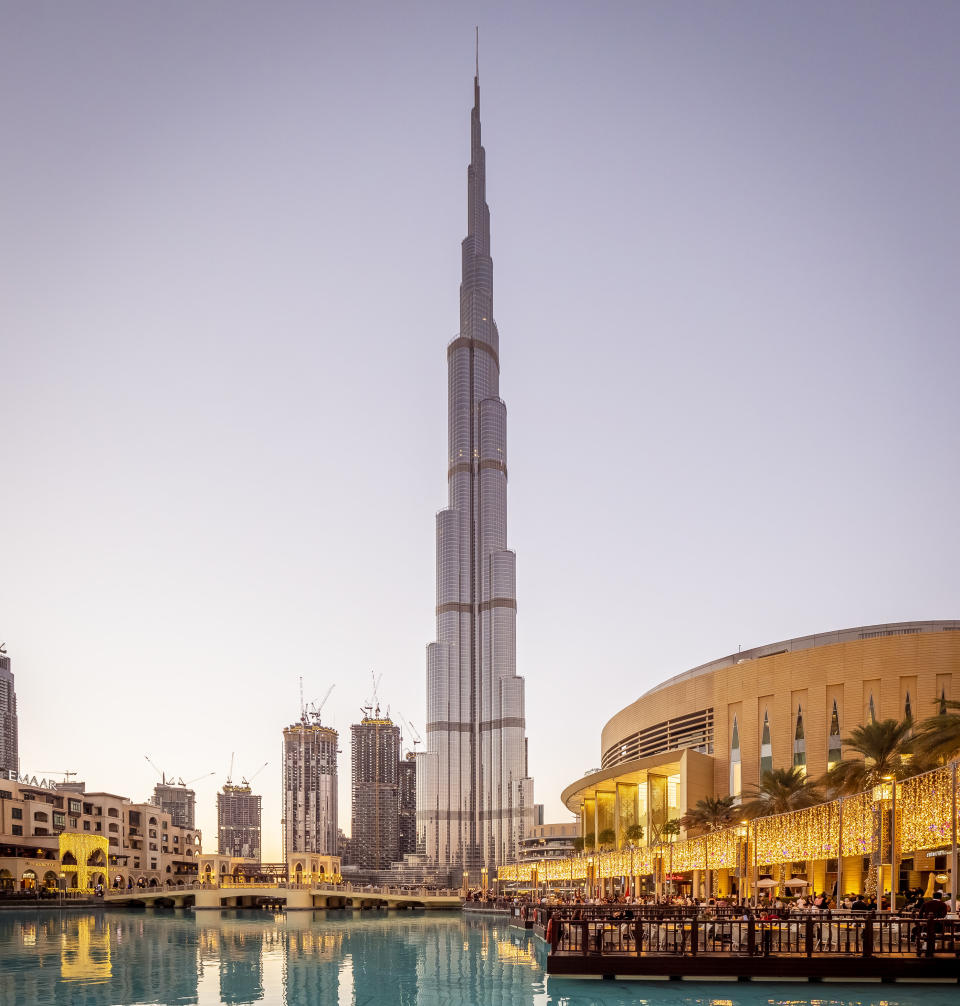 A very tall, thin, tapered building an in urban setting near a bridge over a body of water