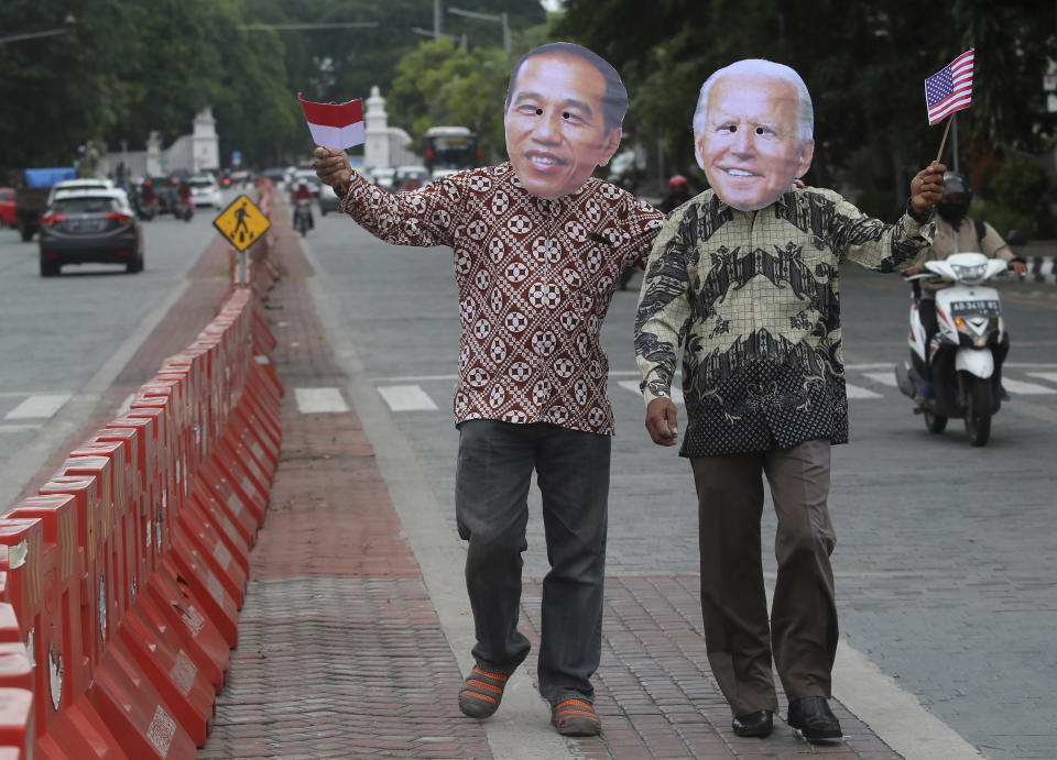 Local activists Mayor Haristanto, left, and Yenyen Wahyono wear masks of Indonesian President Joko Widodo and U.S. President-elect Joe Biden to congratulate him ahead of his inauguration ceremony, in Solo, Central Java, Indonesia, Wednesday, Jan. 20, 2021. (AP Photo/Sahistyo)