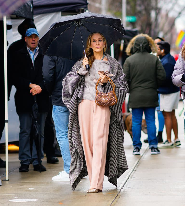 Sarah Jessica Parker, en el set de And Just Like That en Nueva York con un look casual de pantalones rosa, suéter blanco y cardigan gris 

