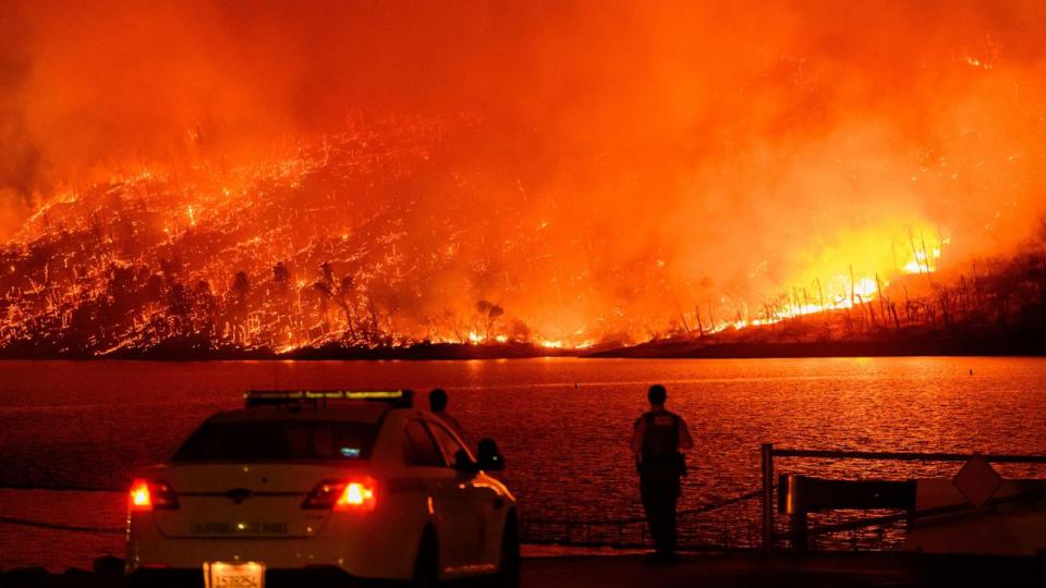 PHOTO: Law enforcement members watch as the Thompson fire burns over Lake Oroville in Oroville, California on July 2, 2024. (Josh Edelson/AFP via Getty Images)