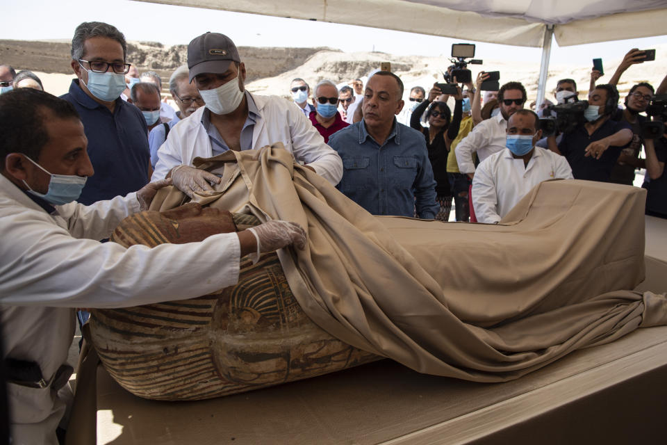 An Egyptian archaeological team opens the sarcophagus that is around 2500 years old at the Saqqara archaeological site, 30 kilometers (19 miles) south of Cairo, Egypt, Saturday, Oct. 3, 2020. Egypt says archaeologists have unearthed about 60 ancient coffins in a vast necropolis south of Cairo. The Egyptian Tourism and Antiquities Minister says at least 59 sealed sarcophagi with mummies inside were found that had been buried in three wells more than 2,600 years ago. (AP Photo/Mahmoud Khaled)