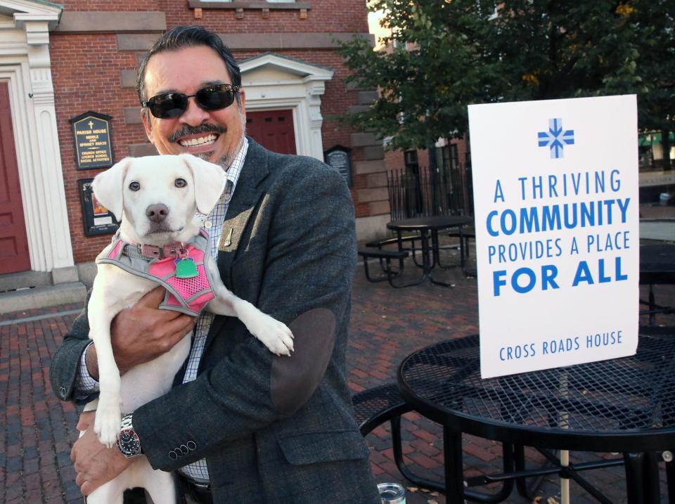 Will Arvelo, Cross Roads House executive director, seen Tuesday, Oct. 3, 2023, has begun a one-man vigil in Portsmouth's Market Square every weekday morning this fall with his dog, Piper Lea. He sits at a table in front of North Church and engages with people on the topic of homelessness.