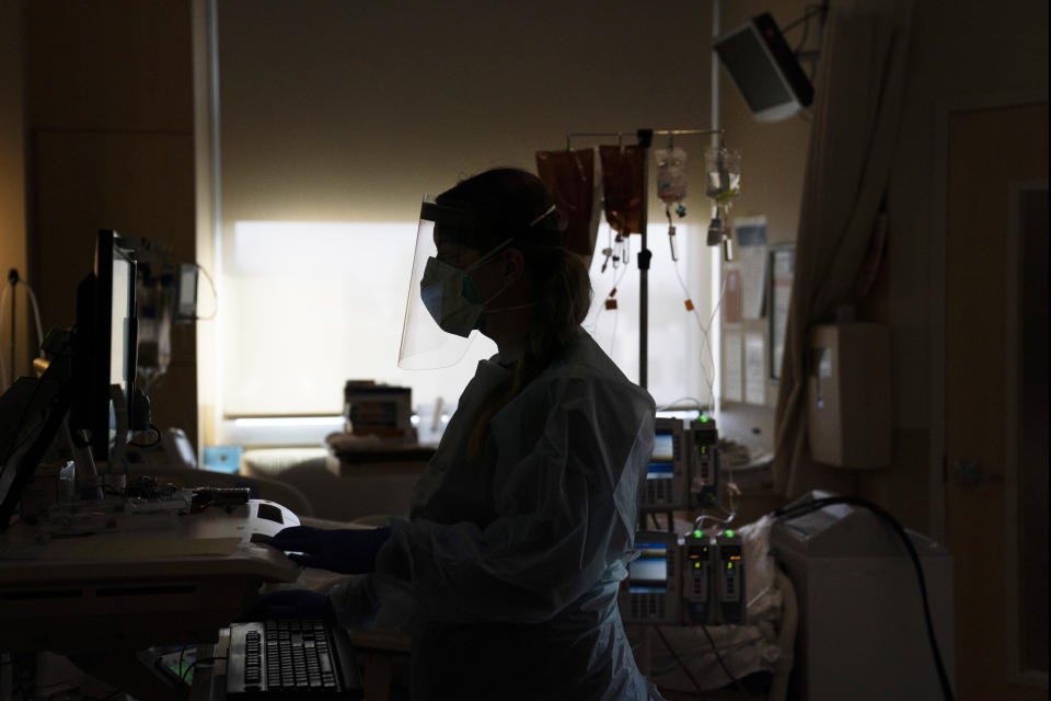 FILE - A registered nurse works on a computer while assisting a COVID-19 patient in Los Angeles. Hospital systems around the country are rolling out fees for some messages that patients send to physicians, saying their providers are increasingly spending more time poring over online queries, some so complex that they require the level of medical expertise normally dispensed during an office visit. (AP Photo/Jae C. Hong, File)