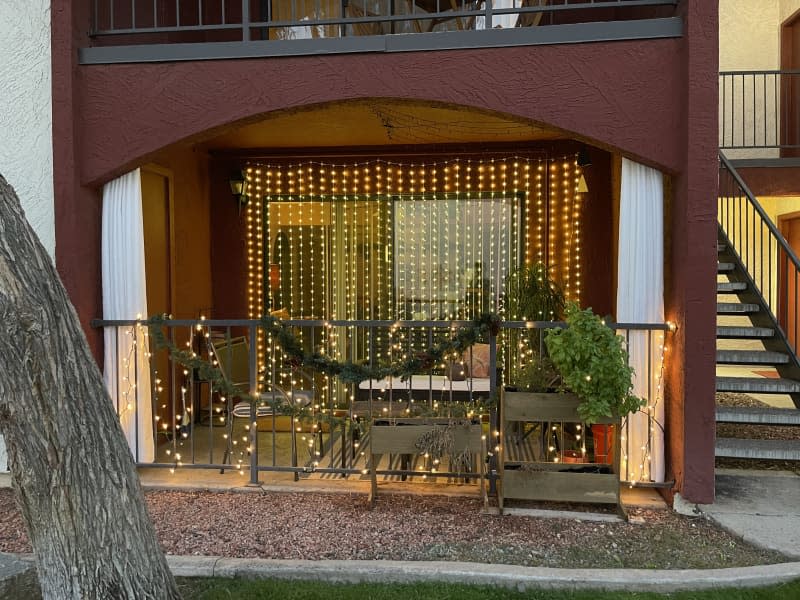 A porch with stings lights, plants and sitting and dining area.