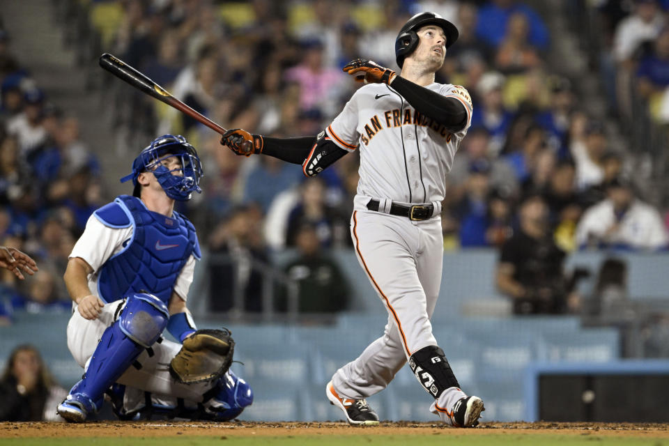 San Francisco Giants' Mike Yastrzemski, right, follows through on a two-run home run next to Los Angeles Dodgers catcher Will Smith during the fourth inning of a baseball game in Los Angeles, Friday, Sept. 22, 2023. (AP Photo/Alex Gallardo)