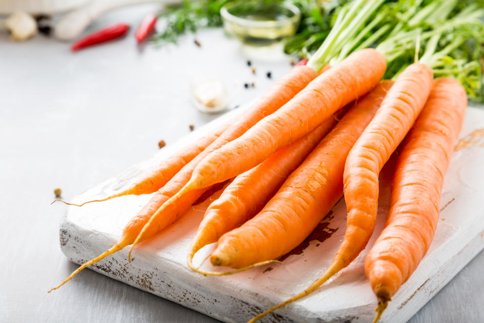 Carrots with vegetarian cooking ingredients. Bio healthy food concept. Organic vegetables on old wooden cutting board. Copy space.