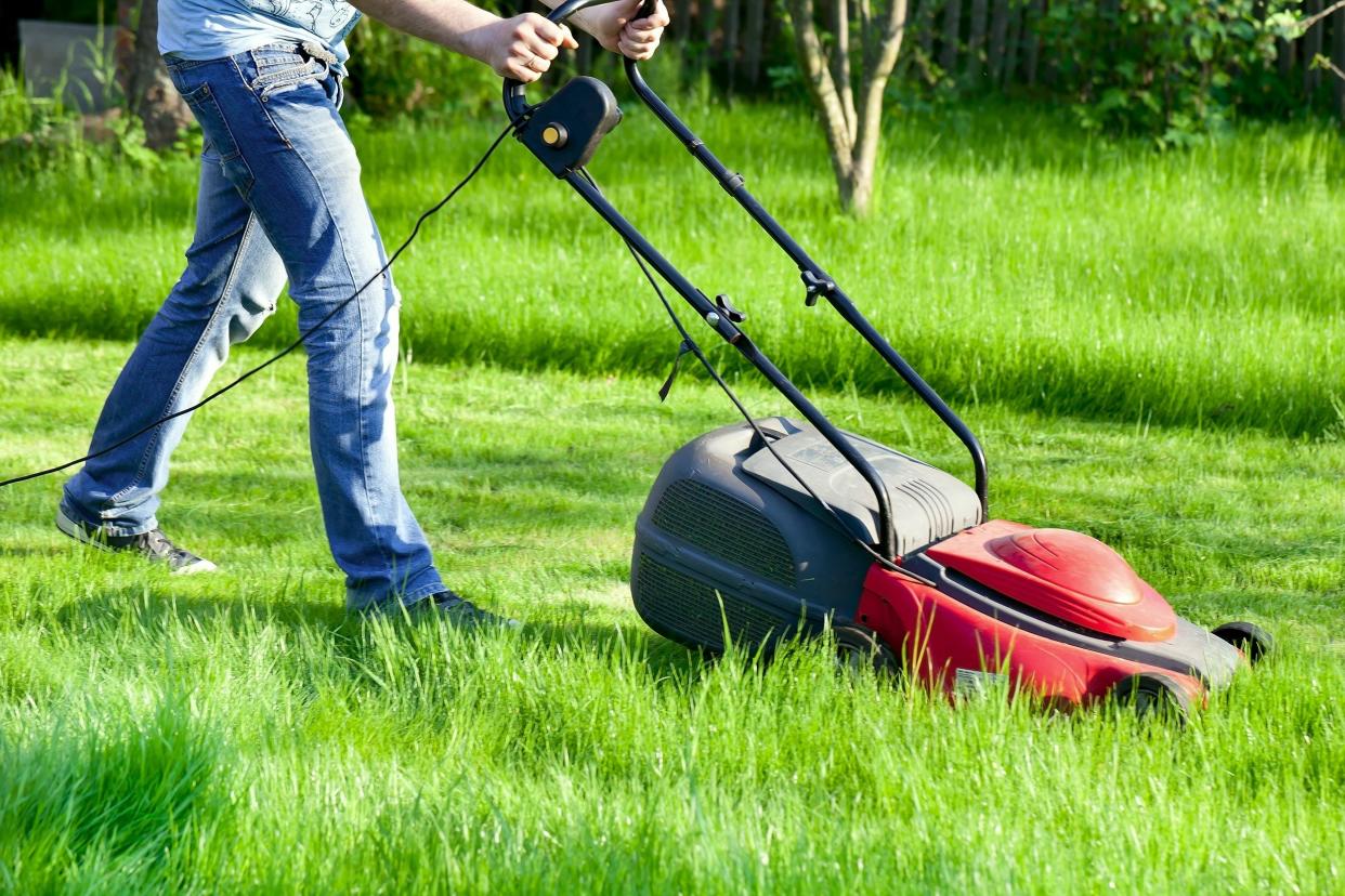 man moves with lawnmower and mows green grass