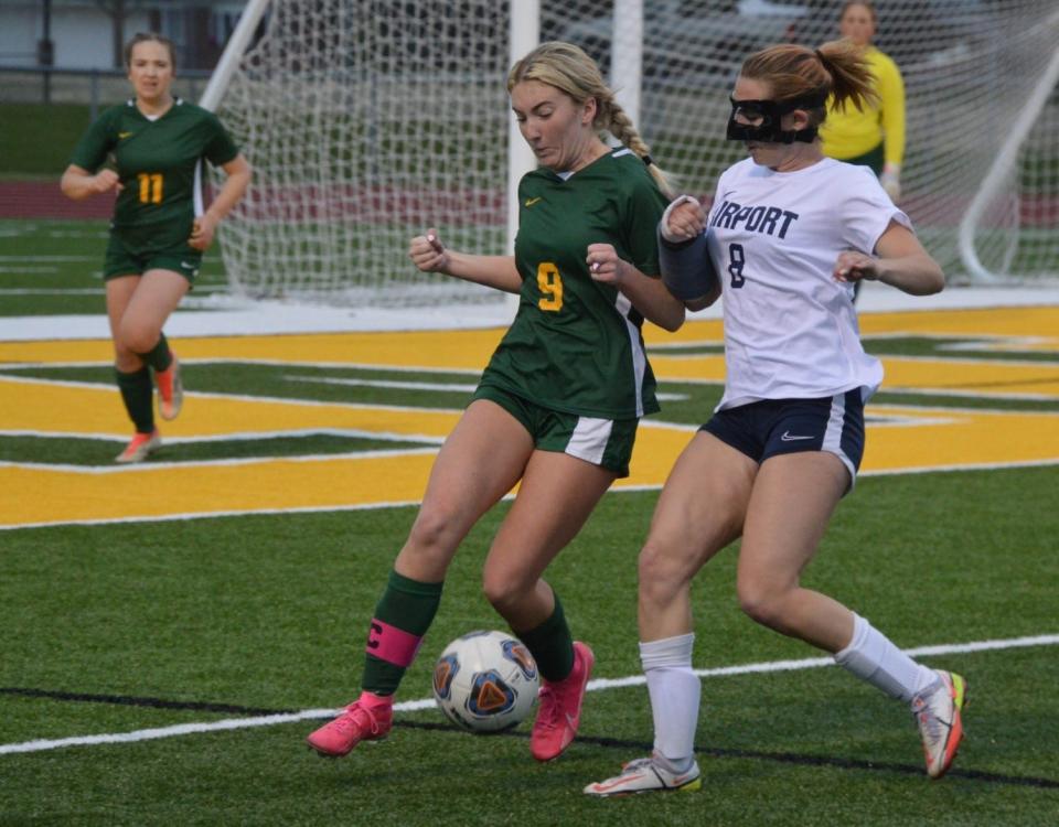 Airport’s Cecelia Ortega (right) and Megan Woelkers of Flat Rock for the ball in a recent game. Ortega was playing with a cast on her broken arm and a mask protecting her broken nose.