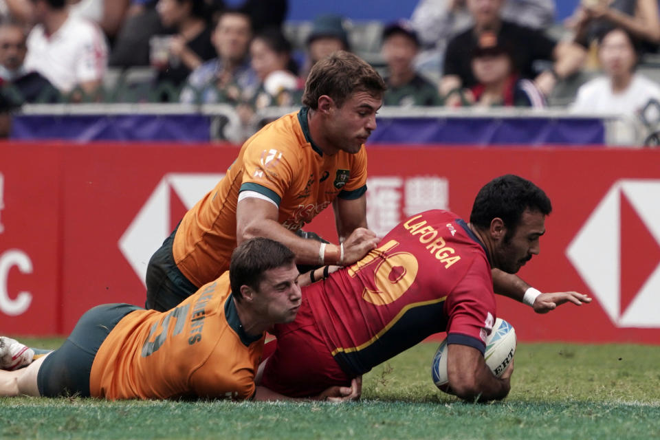 Spain's Alejandro Laforga, right, is tackled by Australia's Tim Clements, bottom left, during the second day of the Hong Kong Sevens rugby tournament in Hong Kong, Saturday, April 1, 2023. (AP Photo/Anthony Kwan)