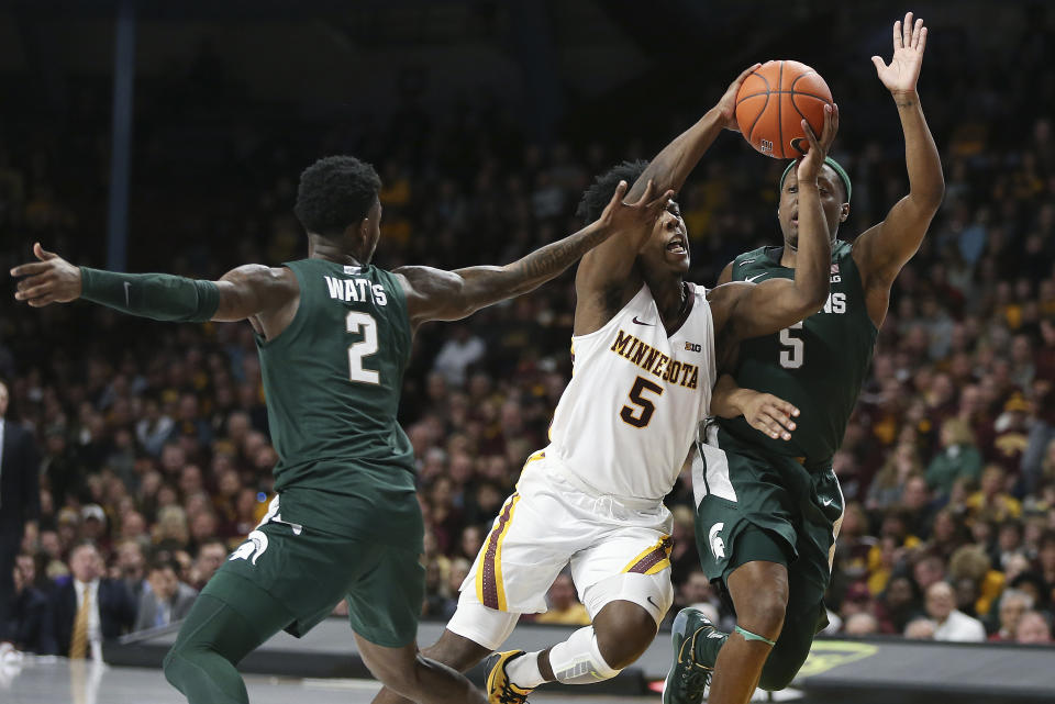 Minnesota's Marcus Carr, center, handles the ball through the defense of Michigan State's Rocket Watts (2) and Cassius Winston, right, during an NCAA college basketball game Sunday, Jan. 26, 2020, in Minneapolis. (AP Photo/Stacy Bengs)