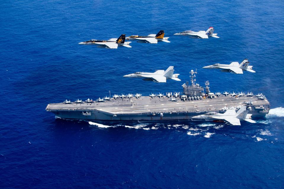 In this handout provided by the U.S. Navy, a combined formation of aircraft from Carrier Air Wing (CVW) 5 and Carrier Air Wing (CVW) 9 pass in formation above the Nimitz-class aircraft carrier USS John C. Stennis (CVN 74). The formation included F/A-18 Hornets from the Black Aces of Strike Fighter Squadron (VFA) 41, the Diamondbacks of Strike Fighter Squadron (VFA) 102, the Eagles of Strike Fighter Squadron (VFA) 115, the Royal Maces of Strike Fighter Squadron (VFA) 27, the Vigilantes of Strike Fighter Squadron (VFA) 151, and the Warhawks of Strike Fighter Squadron (VFA) 97. The Nimitz-class aircraft carriers USS John C. Stennis and USS Ronald Reagan (CVN 76) are conducting dual aircraft carrier strike group operations in the U.S. 7th Fleet area of operations in support of security and stability in the Indo-Asia-Pacific.