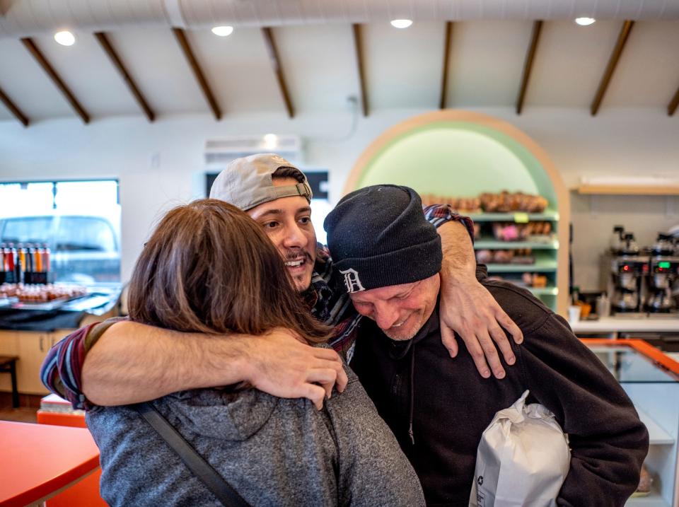 Donut Villa owner Gabriel Gutierrez hugs Debra Ryder, left, of Detroit and her husband Kevin Ryder, right, while talking with the couple after they stopped in to purchase paczki on Tuesday, Feb. 13, 2024, at the shop that is located in Southwest Detroit and recently reopened following renovations.