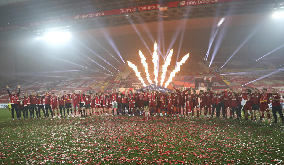 Fireworks explode behind as Liverpool's Jordan Henderson and team members celebrate with the English Premier League trophy aloft after it was presented following the Premier League soccer match between Liverpool and Chelsea at Anfield stadium in Liverpool, England, Wednesday, July 22, 2020. (Phil Noble/Pool via AP)